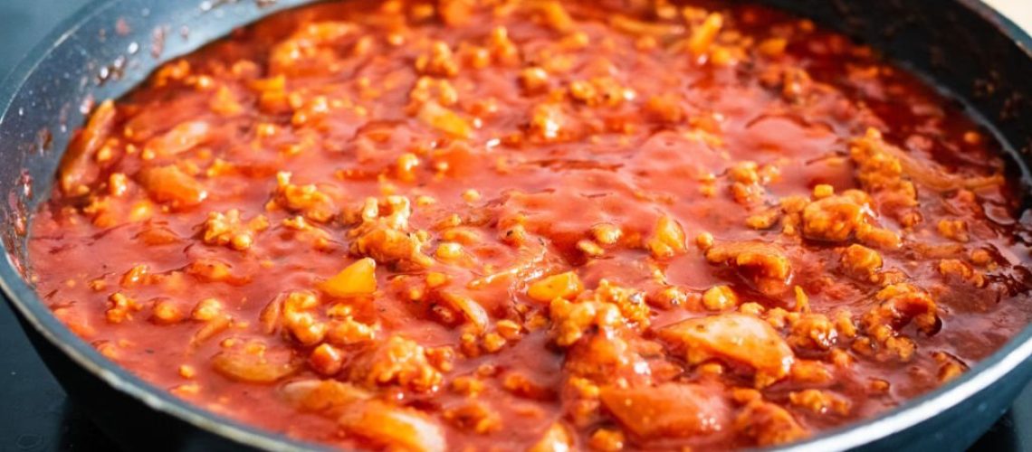 Cooking minced pork meat in tomato sauce in pan
